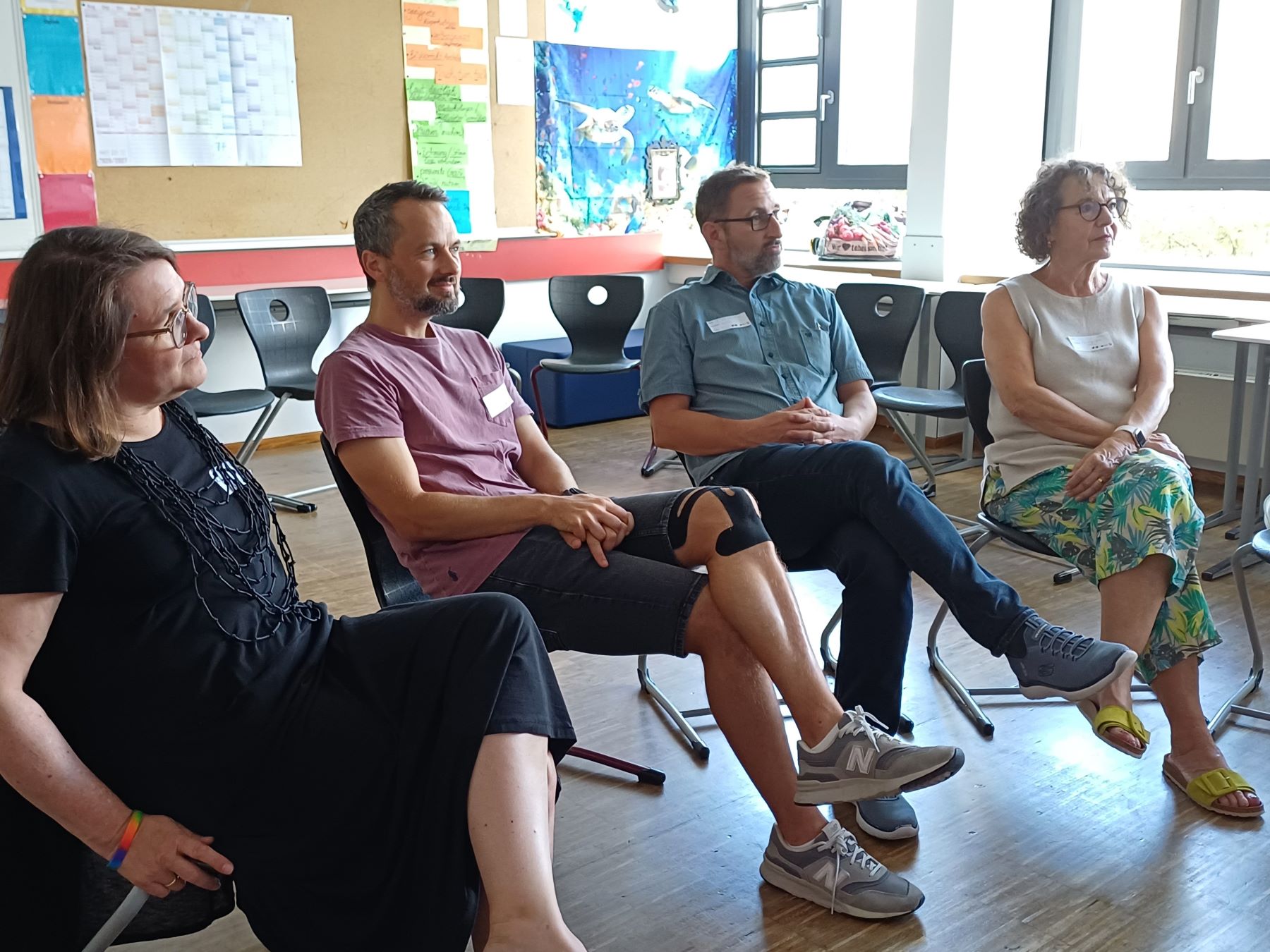 Vier Teilnehmende verfolgen die Arbeit in einer Workshopgruppe.